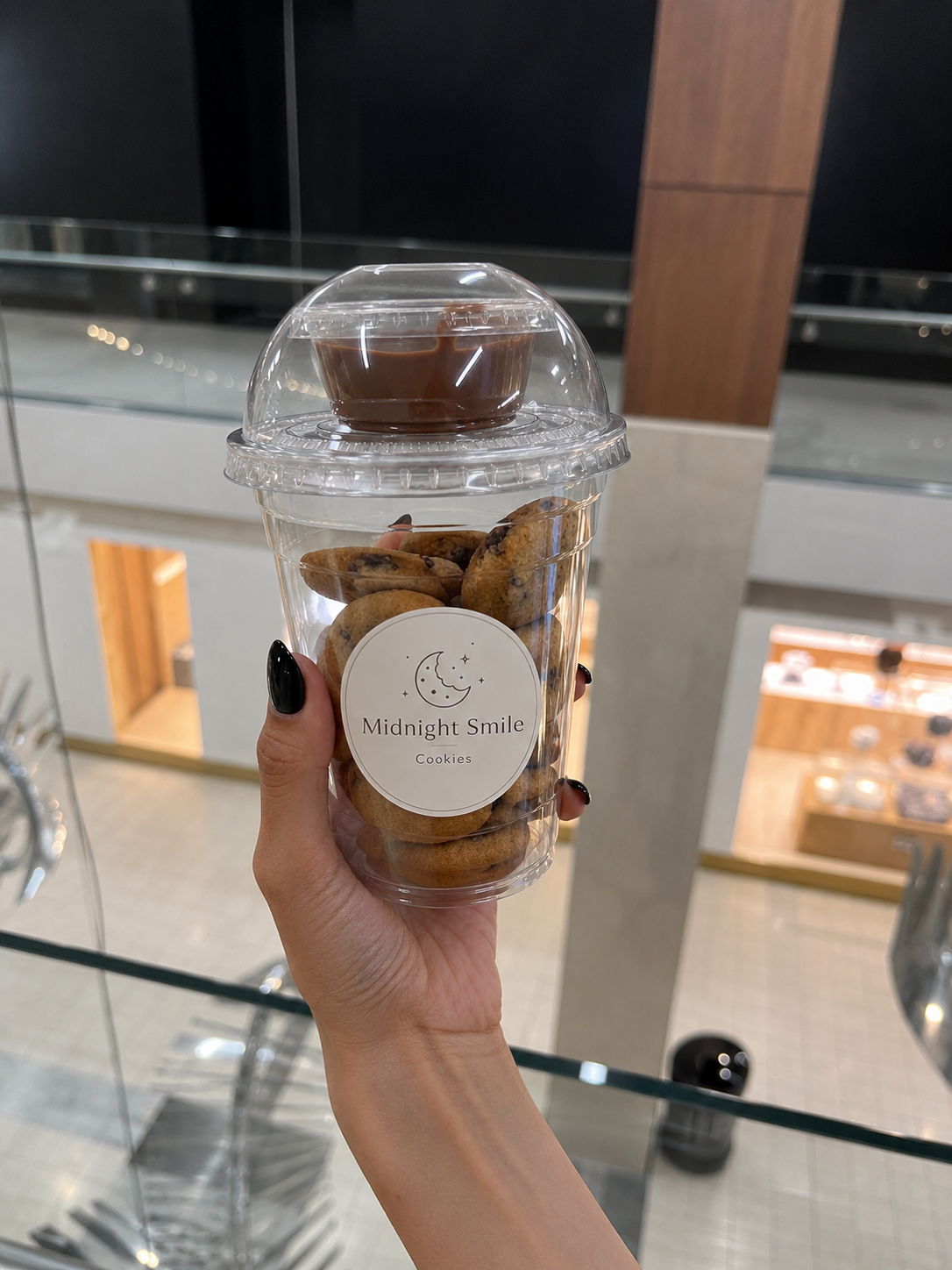 Hand holding a Midnight Smile Cookies cup filled with mini chocolate chip cookies and a Nutella dipping sauce on top
